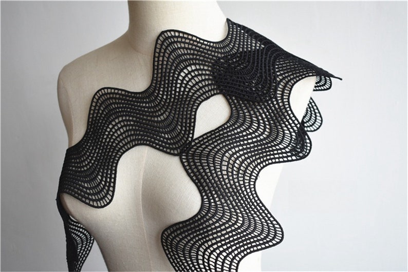 May include: Black lace fabric with a wavy, abstract design. The fabric is delicate and intricate, with a fine mesh pattern.