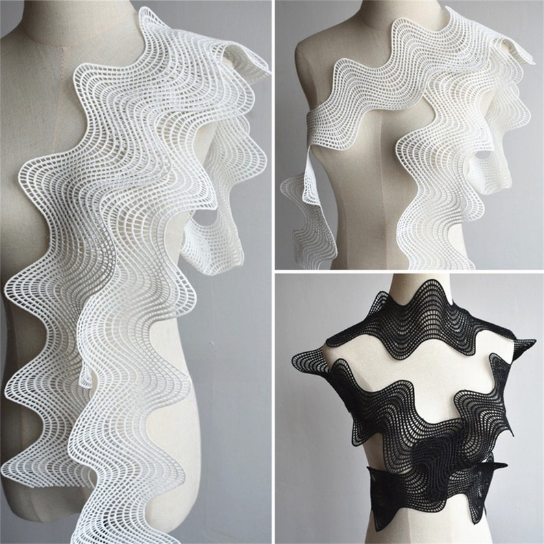 May include: White and black wavy lace trim with a geometric pattern. The lace is shown on a dress form.