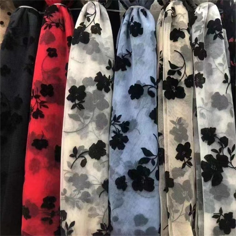 May include: Five different sheer fabrics with black floral embroidery. The fabrics are in black, red, white, light blue, and cream.