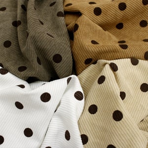 May include: Four different fabrics with brown polka dots on a white, beige, brown, and olive green background. The fabrics are all ribbed and have a soft, textured feel.