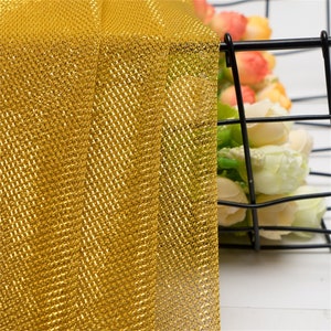 May include: Gold mesh fabric with a fine, even weave. The fabric has a slight sheen and is ideal for crafting or decorating.