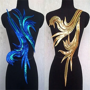 May include: Two sequined fabric appliques in the shape of stylized leaves. The applique on the left is blue and green, while the applique on the right is gold.