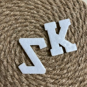 May include: White felt letters, the letter Z and the letter K, on a brown burlap background.