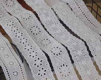 May include: White cotton lace trim with various patterns and scalloped edges. The lace is arranged in rows, showcasing different designs.
