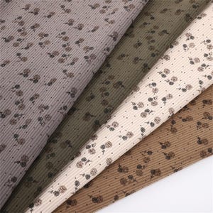 Op de afbeelding: Close-up van vier stoffen stalen in verschillende neutrale kleuren: mauve, olijfgroen, crème en bruin. Elk staal heeft een geribbelde textuur en een herhalend patroon van kleine bloemmotieven in bruin- en zwarttinten.