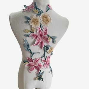 Può includere: Un'applicazione floreale con fiori rosa, bianchi e gialli e foglie verdi. L'applicazione è realizzata in tessuto ricamato ed è perfetta per aggiungere un tocco di eleganza a vestiti o artigianato.