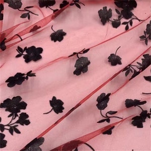 May include: Red sheer fabric with black floral embroidery. The fabric has a delicate, almost translucent quality.