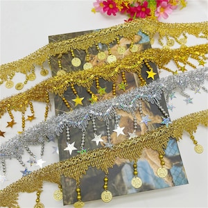 May include: Gold and silver trim with star and coin accents. The trim features dangling beads and fringe.