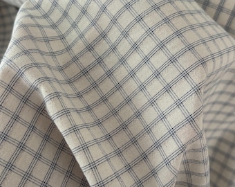 Könnte beinhalten: Nahaufnahme eines Stoffes mit weißem Hintergrund und blauem Karomuster. Der Stoff ist gefaltet und zeigt die Textur und das Gewebe des Materials. Die blauen Linien bilden ein gitterartiges Design auf der Oberfläche.