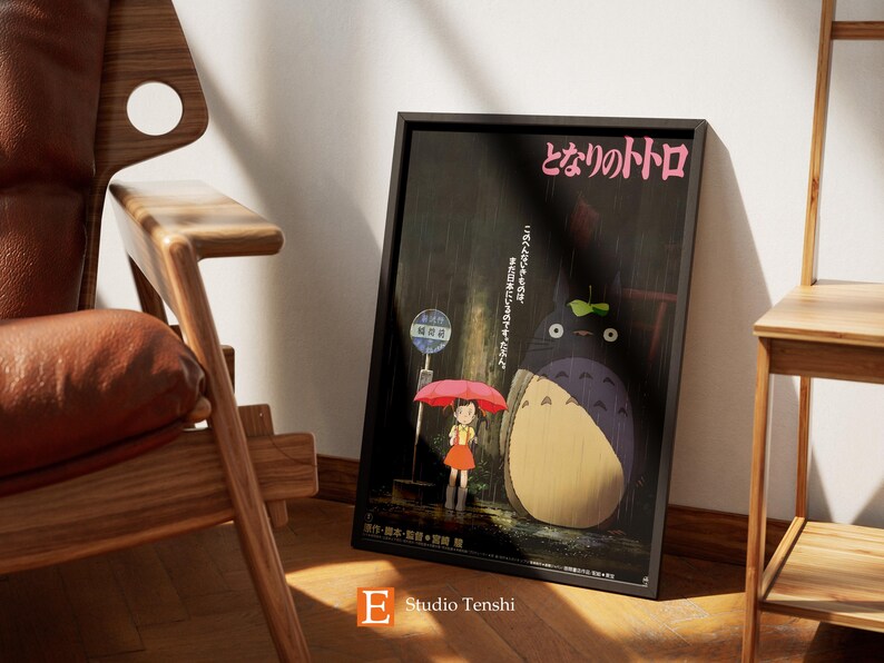 Puede incluir: Un p&oacute;ster enmarcado en negro con el texto japon&eacute;s "となりのトトロ" (Totoro) y una ilustraci&oacute;n de una gran criatura peluda gris con una ni&ntilde;a peque&ntilde;a sosteniendo una sombrilla rosa bajo la lluvia.
