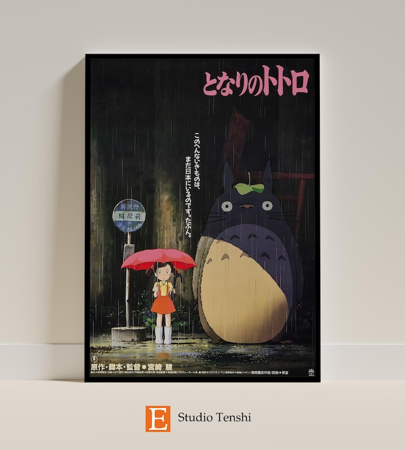 Puede incluir: Un p&oacute;ster vintage para la pel&iacute;cula de Studio Ghibli "Mi vecino Totoro" que muestra a una ni&ntilde;a con un paraguas rosa de pie junto a un gran Totoro gris bajo la lluvia. El p&oacute;ster tiene texto japon&eacute;s que dice "となりのトトロ" y "このへんないきものは、まだ日本にいるのです。たぶん。"  El p&oacute;ster tambi&eacute;n incluye el texto "原作・脚本・監督・宮崎駿" y "E Studio Tenshi".