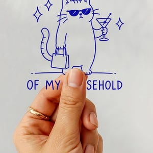 May include: A clear sticker featuring a blue line drawing of a cat wearing sunglasses, holding a shopping bag and a martini glass. The text reads I AM THE PRIMARY BREADLOSER OF MY HOUSEHOLD, accompanied by four-pointed star accents on both sides.