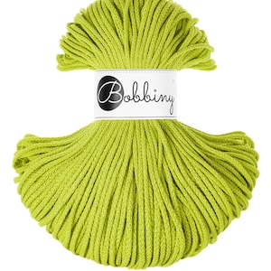 May include: A skein of bright green yarn, tightly wound and ready for crafting. The yarn is a vibrant, spring-like green, and a white label with the word "Bobbing" in a stylish script is wrapped around the center.