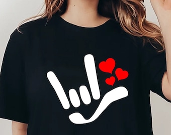 May include: Black t-shirt with a white sign language hand symbol for 'I love you' and three red hearts.