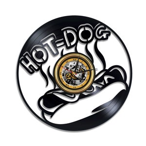 May include: Black vinyl record clock with a gold clock face and Roman numerals. The clock is shaped like a hand holding a hot dog with the text "HOT-DOG" above the hand.