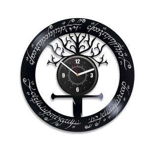 May include: Black wall clock with a tree design and a clock face. The clock features white lettering and hands, and a circular design with text around the edge. The clock is a unique decorative item.