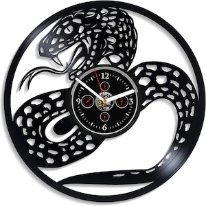 May include: Black vinyl record clock featuring a snake design. The clock face is black with white numbers and hands. The snake is coiled around the clock face and has a detailed, textured design.
