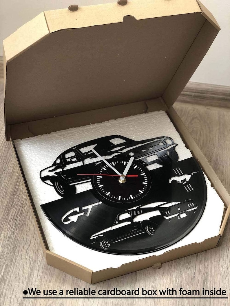 May include: A black vinyl record clock featuring a silhouette of a Ford Mustang GT. The clock is packaged in a cardboard box with foam padding.