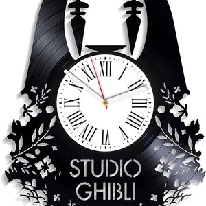 May include: Black vinyl record clock featuring a silhouette of No Face from the Studio Ghibli film Spirited Away. The clock face is white with black Roman numeral hour markers and black hands. The clock is surrounded by a floral design.