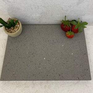 May include: A close-up of a gray countertop with a speckled pattern. There are three red strawberries on the countertop.