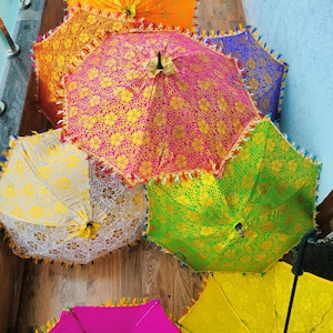 May include: A collection of colorful, decorative umbrellas. The umbrellas feature intricate gold floral patterns on a variety of vibrant backgrounds, including pink, orange, green, yellow, and blue. Each umbrella has a decorative fringe.