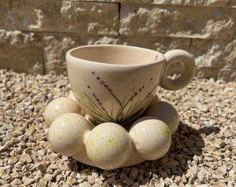 Könnte beinhalten: Eine weiße Teetasse aus Keramik mit Blumenmuster und einer passenden Untertasse mit einem einzigartigen, geblähten Rand.