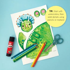 May include: A craft project featuring a green watercolor dinosaur illustration with a blue frill, along with colored pencils, scissors, and a glue stick. The text says, "TIP: Start with watercolors, then add details using pencils or markers!"