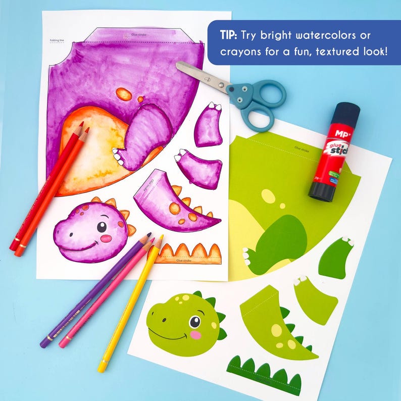 May include: A craft project featuring dinosaur cutouts, colored pencils, scissors, and glue stick. The dinosaur parts are printed on white paper and colored with purple, orange, and green hues. Text on the image reads: "TIP: Try bright watercolors or crayons for a fun, textured look!"
