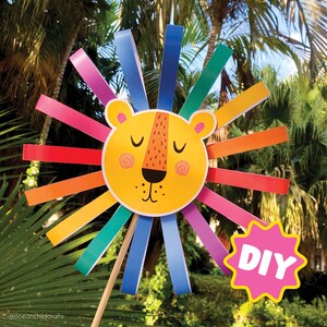 K&ouml;nnte beinhalten: Ein farbenfrohes Papierl&ouml;wen-Bastelwerk mit einem gelben Gesicht und einer Regenbogenm&auml;hne. Der L&ouml;we ist an einem Holzstab befestigt und hat ein rosa DIY-Etikett.