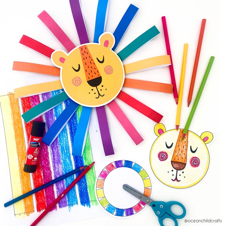 K&ouml;nnte beinhalten: Ein farbenfrohes Bastelprojekt mit einem L&ouml;wenkopf, dessen M&auml;hne aus regenbogenfarbenen Papierstreifen besteht. Das Bild zeigt au&szlig;erdem einen Farbkreis, Buntstifte und einen Klebestift.