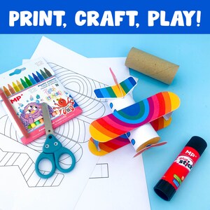 May include: A printable craft kit for making a rainbow airplane. The kit includes a paper airplane template, a cardboard tube, glue stick, and crayons. The text on the packaging reads "Print, Craft, Play!" and "Pastel Crayons".