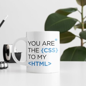 May include: White ceramic mug with black text that reads "You are the {CSS} to my <HTML>"