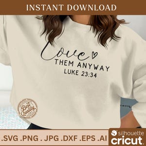 Peut inclure: Sweat-shirt crème avec l'inscription "Love Them Anyway" et le verset biblique Luc 23:34 en écriture noire. L'image comprend également un badge "Best Quality Guarantee" et des informations sur le type de fichier.