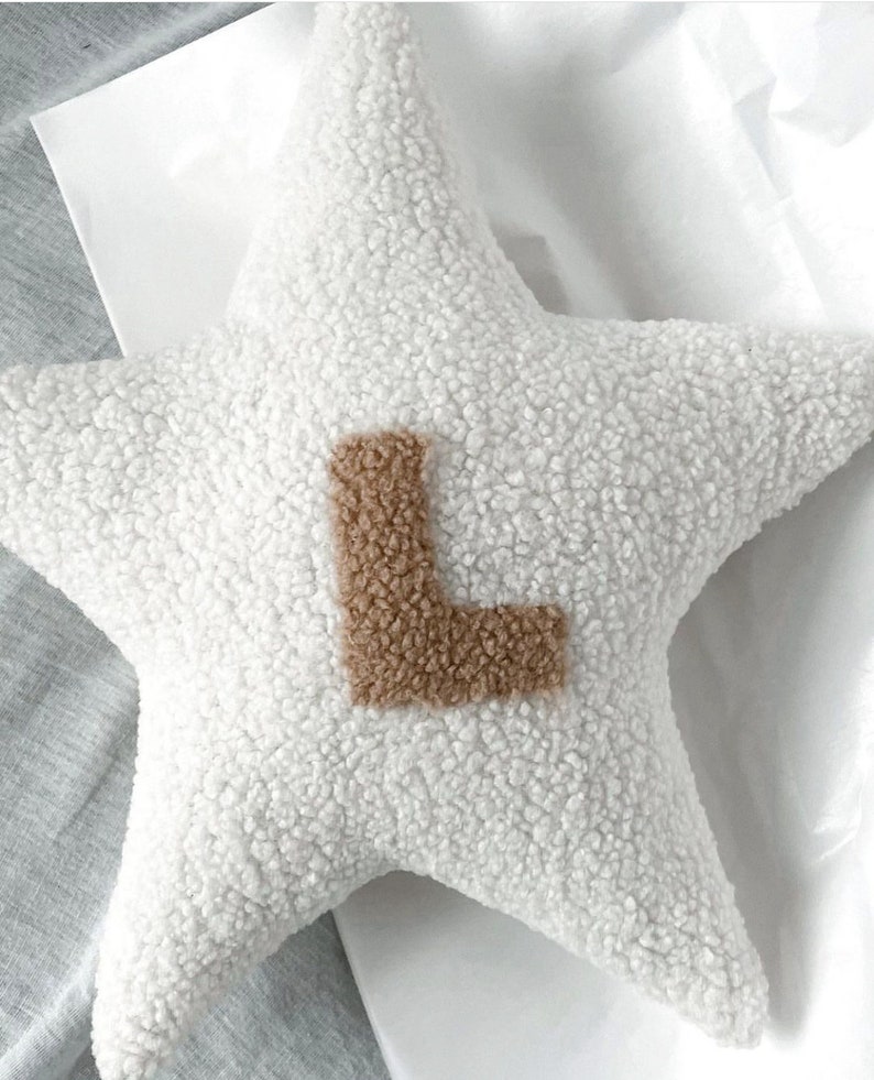 以下が含まれることがあります： 中央に茶色のLの文字がついた白い星型のクッション