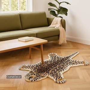 May include: A beige and brown leopard print rug shaped like a jaguar is on a hardwood floor. The rug is in front of a wooden coffee table and a green sofa. A beige throw blanket is draped over the sofa.