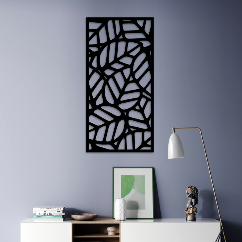 May include: A black, rectangular wall art piece featuring a leaf design. The leaves are cut out, creating a negative space effect. The artwork is mounted on a light gray wall, adding a modern touch to the decor.