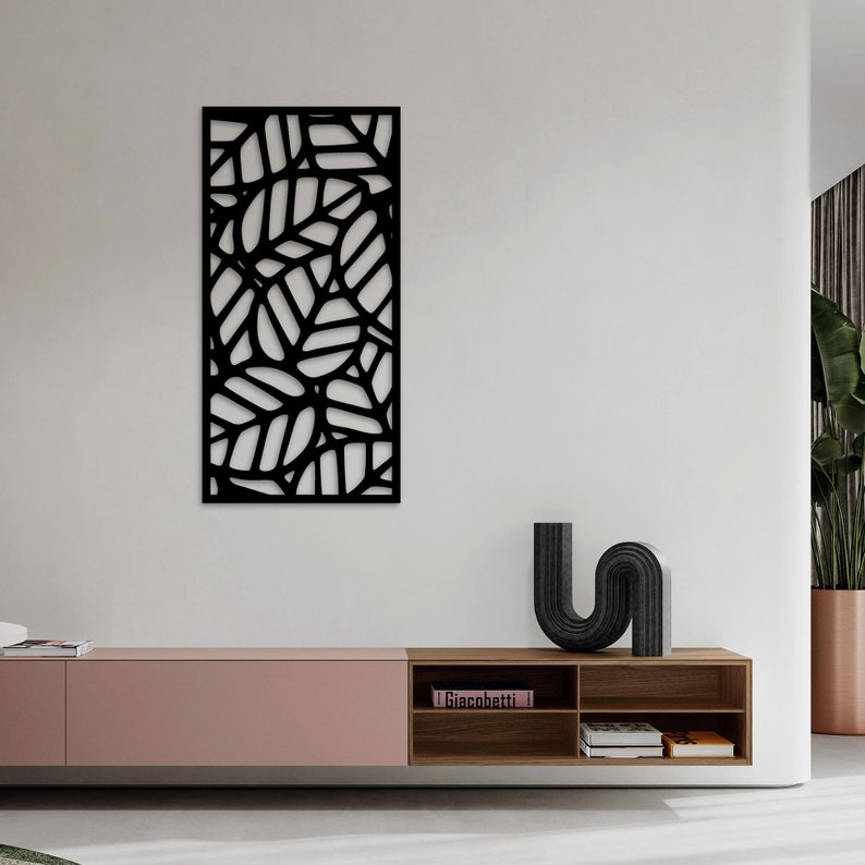 May include: Black metal wall art featuring a leaf design. The artwork is rectangular and has a cut-out pattern of overlapping leaves. The piece is mounted on a white wall, adding a modern touch to the room's decor.