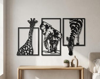 May include: Black metal wall art set featuring a giraffe, elephant, and zebra, each within a rectangular frame. The giraffe has a spotted pattern, the elephant is facing forward, and the zebra is drinking. The artwork is displayed on a white wall above a wooden table.