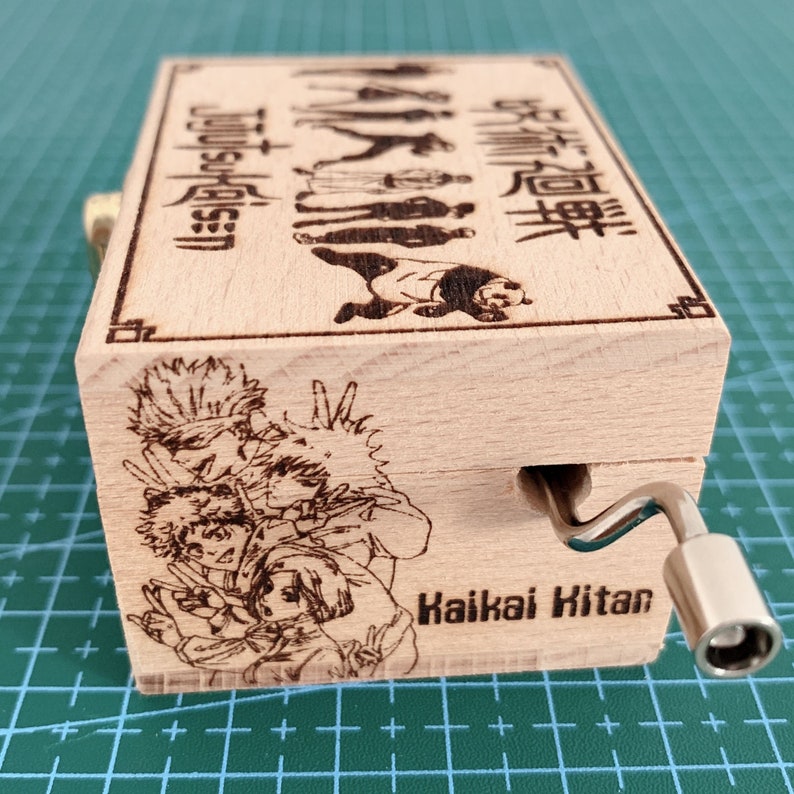 Puede incluir: Una caja de m&uacute;sica de madera con una manivela en el lateral. La caja est&aacute; decorada con una imagen de personajes del anime "Jujutsu Kaisen" y el texto "Jujutsu Kaisen" y "Kaikai Kitan".