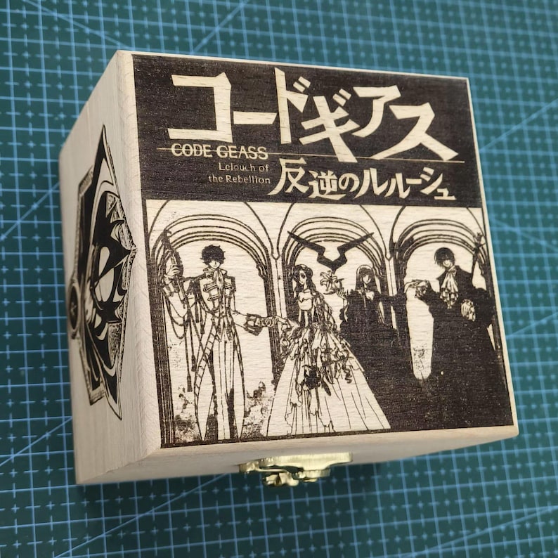May include: A wooden box with a hinged lid and a metal clasp. The box is decorated with a laser-engraved image of characters from the anime series Code Geass: Lelouch of the Rebellion. The text "Code Geass Lelouch of the Rebellion 反逆のルルーシュ" is also engraved on the box.