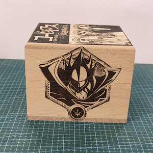 May include: A wooden box with a black and white illustration of a character from the anime "Code Geass." The box has the Japanese text "コードギアス 反逆のルルーシュ" on the top.