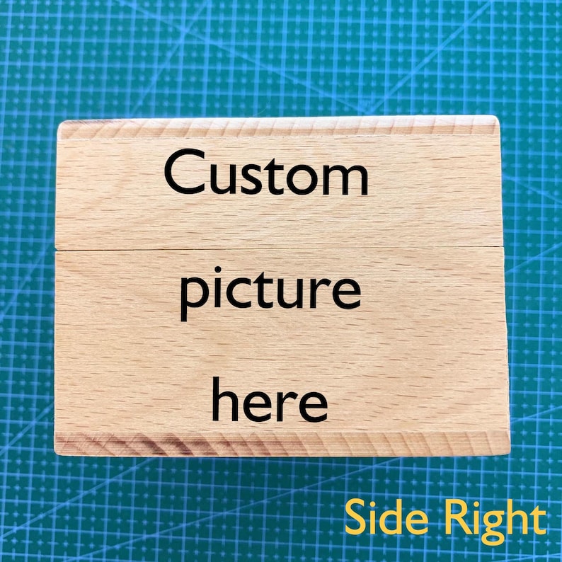 May include: A wooden block with the text "Custom picture here" on it. The block is light brown and has a natural wood grain. The text is in black and is centered on the block. The block is on a green surface.