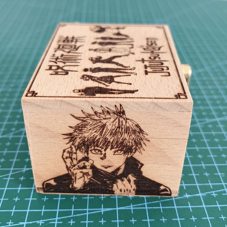 Puede incluir: Una caja de madera con un personaje del anime Jujutsu Kaisen en la parte delantera. La caja est&aacute; grabada con el texto "Jujutsu Kaisen" y caracteres japoneses.
