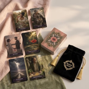 May include: A deck of tarot cards featuring illustrated scenes, including The Empress, Serenity, The Lovers, Wheel of Fortune, Ace of Swords, and King of Pentacles. A black velvet drawstring pouch with gold tassels and the text Rooted Heart is included.