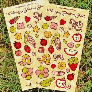 May include: Two whimsical sticker sheets with various colorful illustrations. Designs include ladybugs, strawberries, bows, buttons, and more. The text "strawberrymothco Whimsy Sticker Sheet" is printed at the top.