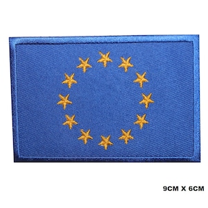 May include: A blue embroidered patch with a circle of 12 gold stars. The patch measures 9 cm by 6 cm.