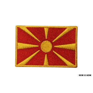 May include: Embroidered patch of the flag of North Macedonia. The flag is red with a yellow sun with eight rays.