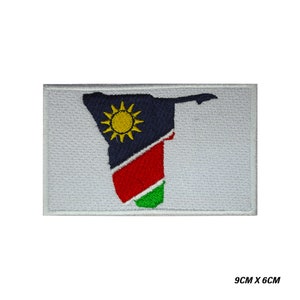 May include: Embroidered patch featuring the outline of Namibia with the Namibian flag colors: blue, red, green, and yellow. The patch is 9 inches by 6 inches.