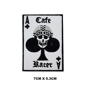 May include: A white patch with black embroidery depicting a playing card with a skull wearing a helmet and goggles. The card is a club and reads "Ace Cafe Racer Ace". The patch measures 7 cm by 5.3 cm.