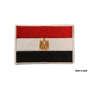 May include: An embroidered patch of the Egyptian flag. The flag is red, white, and black with a gold eagle in the centre. The patch is 9cm by 6cm.
